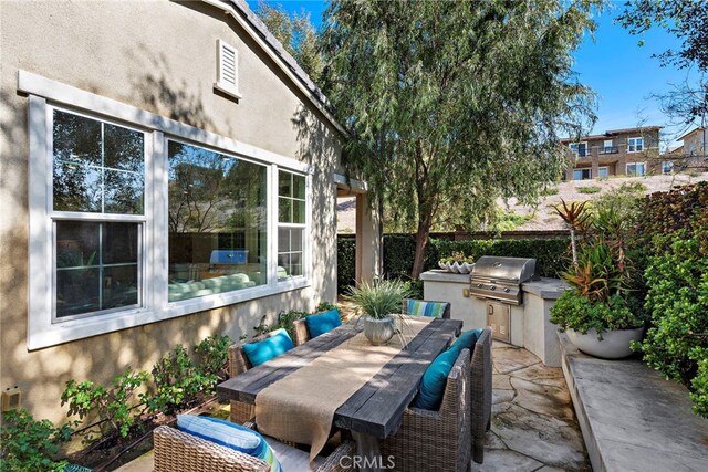 view of patio with exterior kitchen, outdoor dining space, and grilling area