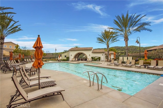 community pool featuring a jacuzzi, fence, and a patio area