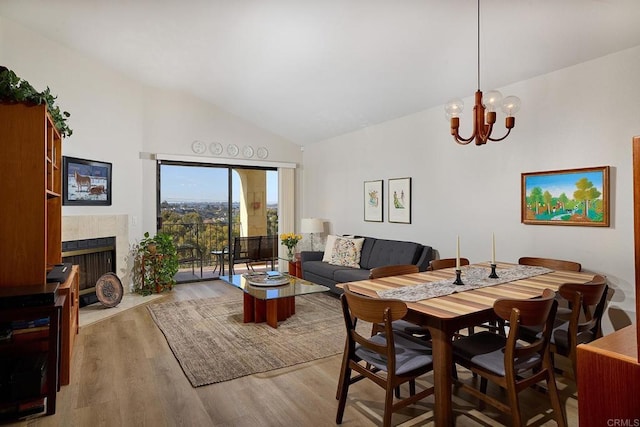 dining area featuring light wood-type flooring, high vaulted ceiling, and an inviting chandelier