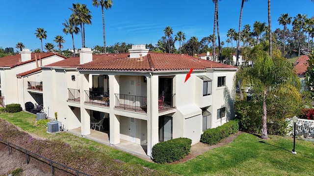 rear view of house featuring a yard, central air condition unit, and a balcony