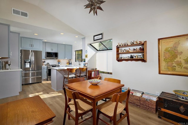 dining room with light hardwood / wood-style floors, lofted ceiling, and sink