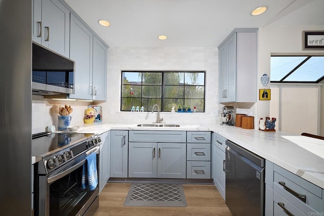 kitchen with a wealth of natural light, stainless steel appliances, light stone counters, and sink