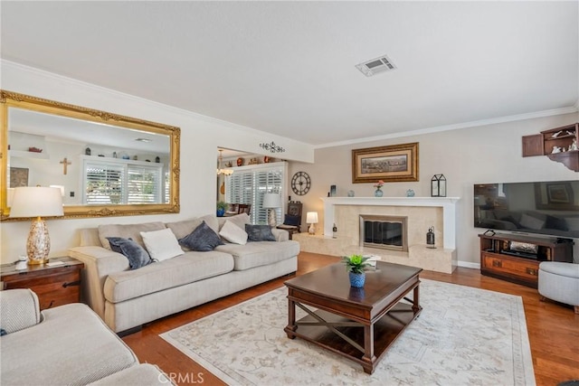 living room with a high end fireplace, hardwood / wood-style floors, and crown molding