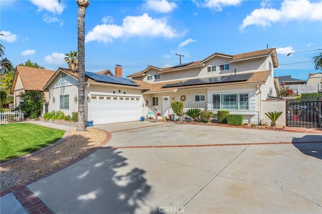 traditional home featuring driveway, an attached garage, fence, and roof mounted solar panels