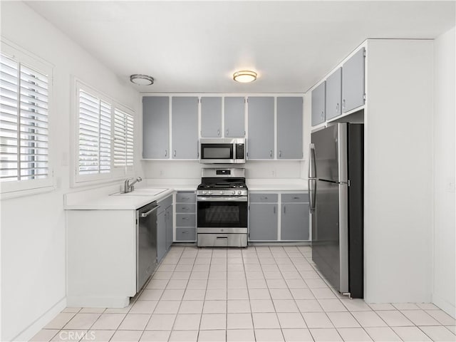 kitchen featuring appliances with stainless steel finishes, gray cabinets, sink, and light tile patterned flooring