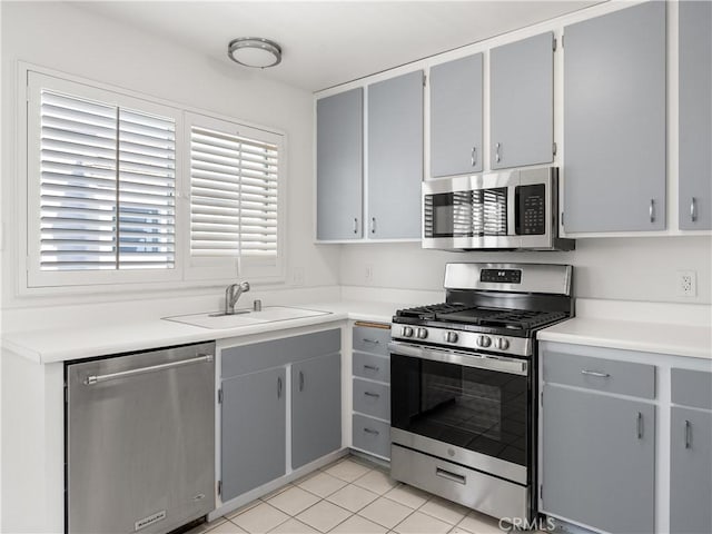 kitchen featuring gray cabinets, stainless steel appliances, light tile patterned flooring, and sink