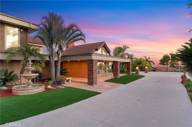 exterior space featuring a tile roof, a lawn, and stucco siding