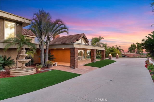 mediterranean / spanish-style house with stucco siding, a yard, a patio, and a tile roof