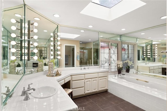 full bath featuring a skylight, a sink, tile patterned floors, and two vanities