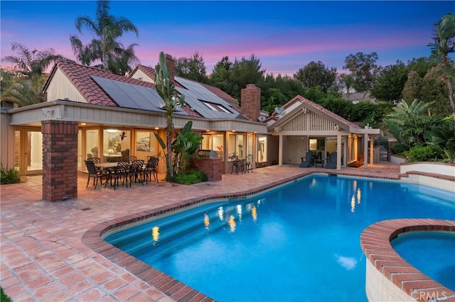 view of swimming pool featuring outdoor dry bar, outdoor dining area, a pool with connected hot tub, and a patio area