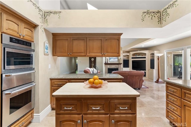 kitchen with brown cabinets, a center island, a warming drawer, stainless steel oven, and open floor plan