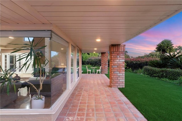 patio terrace at dusk featuring a lawn