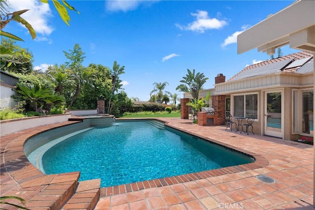 view of swimming pool with a patio area, a pool with connected hot tub, and exterior kitchen