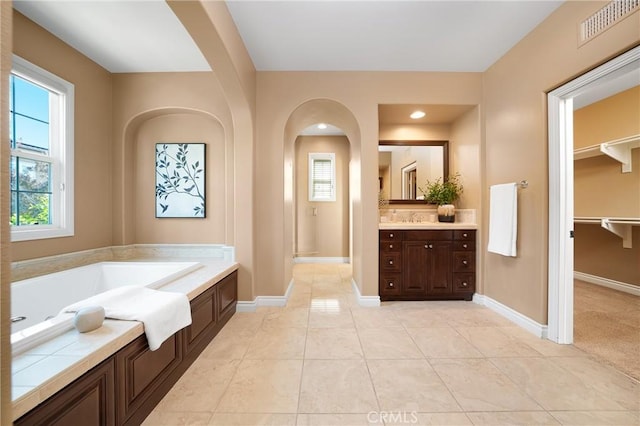 bathroom with a tub to relax in, vanity, and tile patterned floors