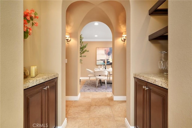 corridor featuring light tile patterned flooring and crown molding