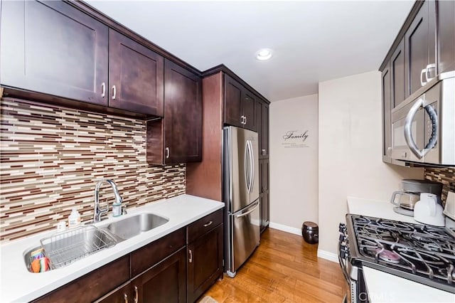 kitchen featuring stainless steel appliances, light hardwood / wood-style flooring, sink, dark brown cabinets, and tasteful backsplash