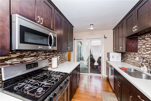 kitchen with light hardwood / wood-style flooring, a barn door, sink, ceiling fan, and appliances with stainless steel finishes