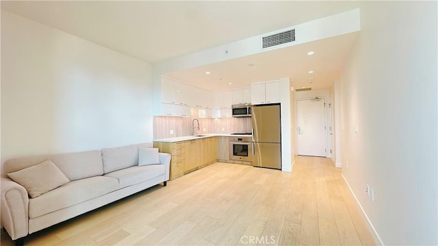 living room with recessed lighting, visible vents, light wood-style floors, and baseboards