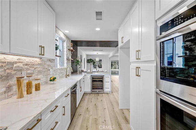 kitchen with wine cooler, white cabinetry, and light stone countertops