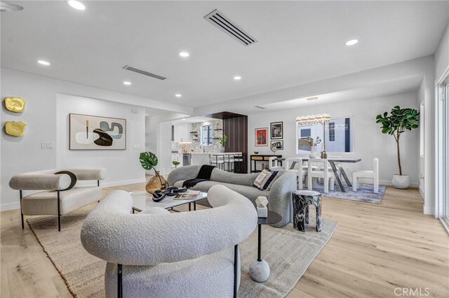 living area with baseboards, light wood-style flooring, visible vents, and recessed lighting