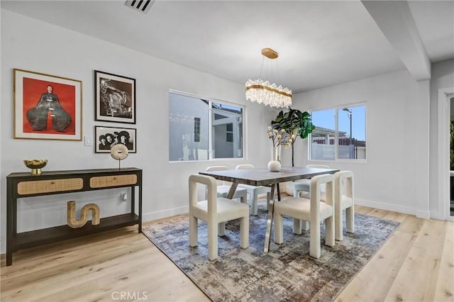 dining space with light wood-type flooring, visible vents, and baseboards