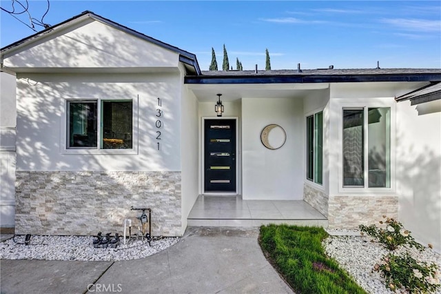 doorway to property featuring stone siding and stucco siding