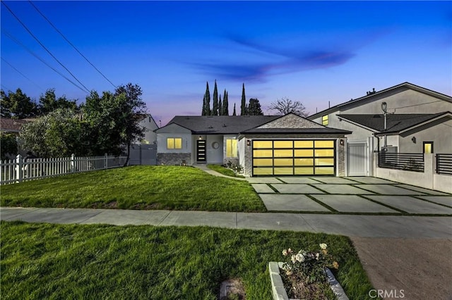 view of front of house with stucco siding, concrete driveway, an attached garage, fence, and a front lawn