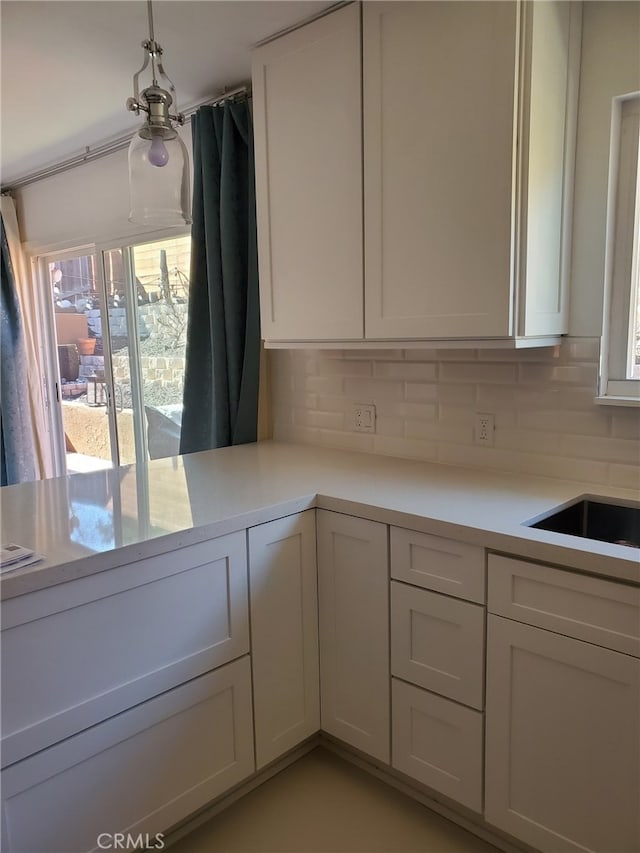 kitchen featuring tasteful backsplash, white cabinets, and light countertops