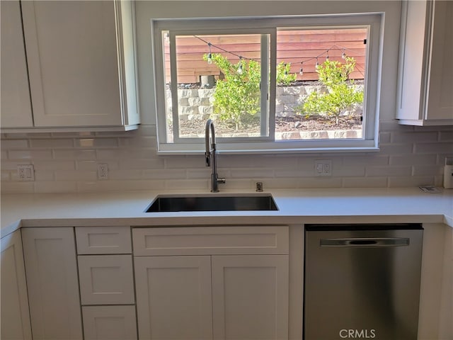 kitchen with a sink, backsplash, white cabinets, light countertops, and dishwasher