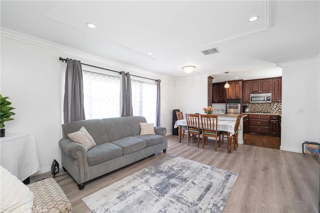 living area with crown molding, light wood-style flooring, and baseboards