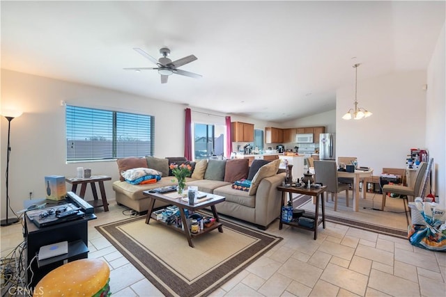 living room featuring ceiling fan with notable chandelier and vaulted ceiling