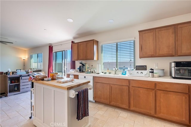 kitchen featuring a kitchen island, sink, ceiling fan, dishwasher, and wooden counters