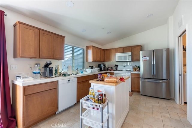 kitchen with white appliances, a center island, and lofted ceiling