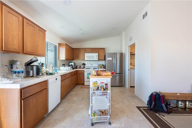 kitchen featuring white appliances, a center island, and lofted ceiling