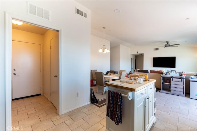 kitchen with a kitchen island, white cabinets, hanging light fixtures, and ceiling fan with notable chandelier