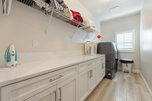 laundry room featuring light hardwood / wood-style flooring, separate washer and dryer, and cabinets