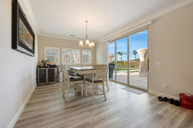 dining space featuring crown molding, a notable chandelier, and light hardwood / wood-style flooring