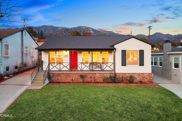 view of front facade with a mountain view, a yard, and covered porch