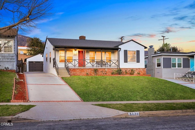 bungalow-style home featuring a garage, a lawn, an outdoor structure, and a porch