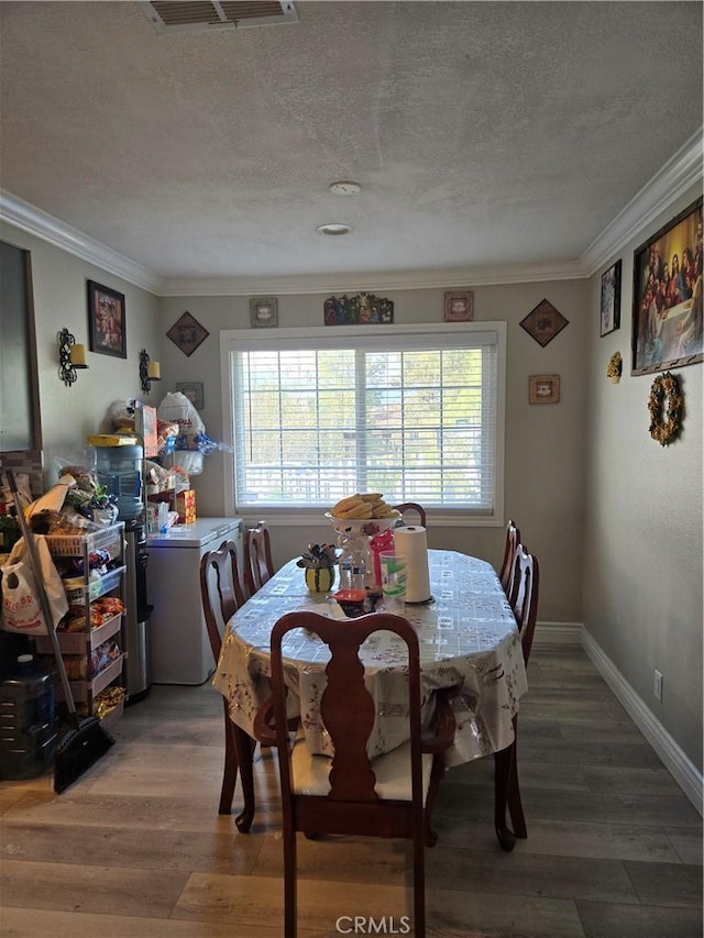 dining room with ornamental molding, wood-type flooring, and a textured ceiling