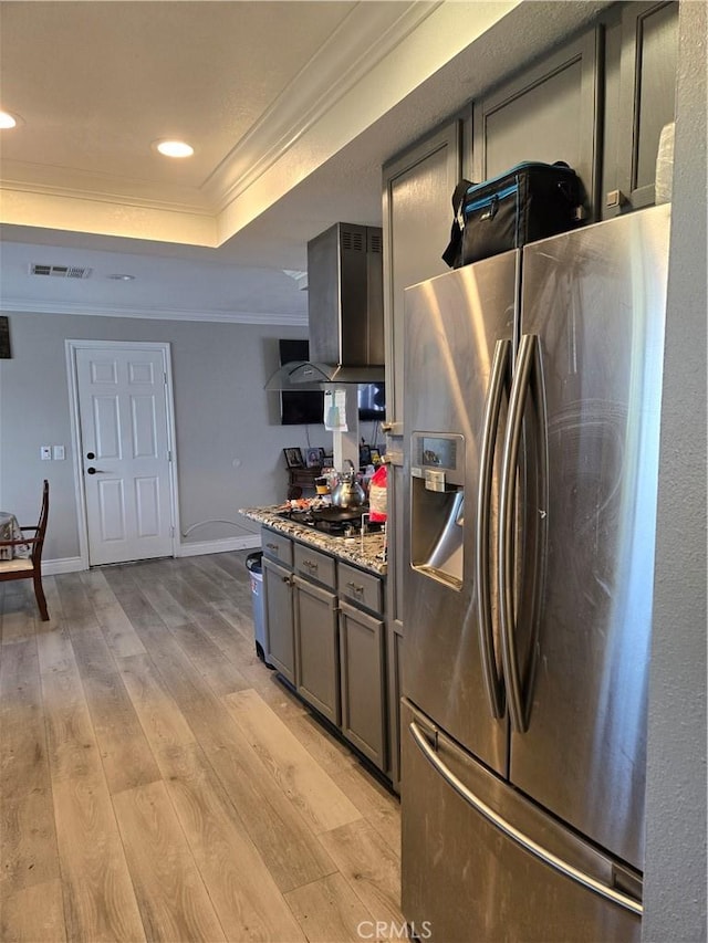 kitchen featuring light hardwood / wood-style flooring, light stone countertops, stainless steel fridge, a raised ceiling, and crown molding