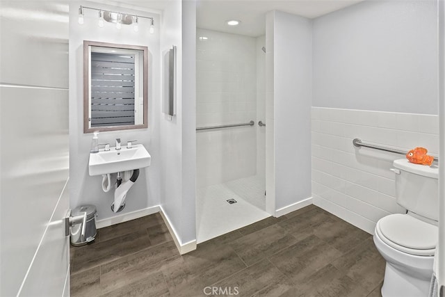 bathroom with tile walls, toilet, walk in shower, and hardwood / wood-style floors