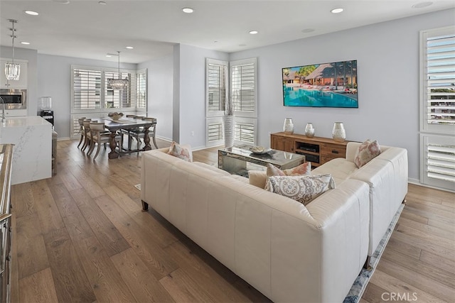 living room featuring an inviting chandelier, a healthy amount of sunlight, and wood-type flooring