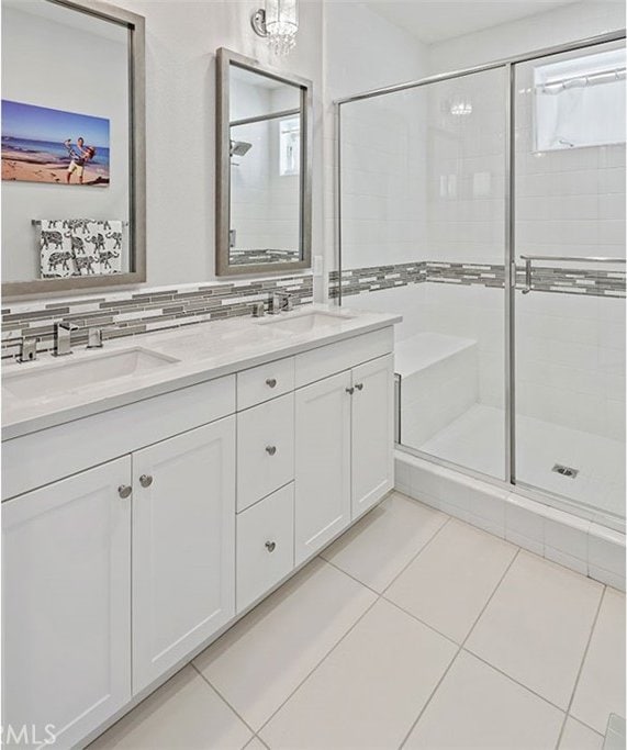 bathroom featuring decorative backsplash, vanity, tile patterned flooring, and a shower with door