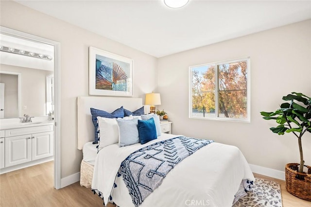 bedroom featuring sink, ensuite bathroom, and light hardwood / wood-style flooring