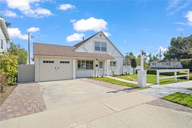 view of front of home with an attached garage, fence, concrete driveway, stucco siding, and a front yard