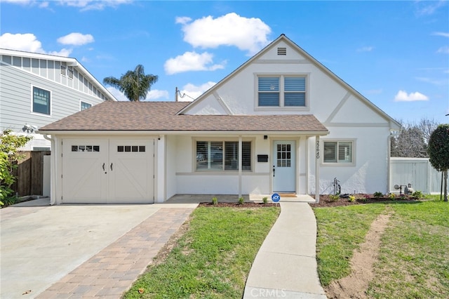 english style home with a garage, fence, driveway, stucco siding, and a front yard