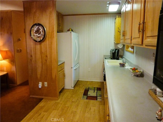 kitchen with white refrigerator, sink, and light hardwood / wood-style flooring