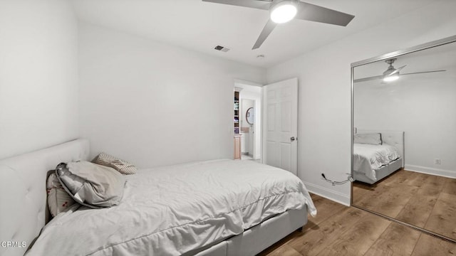 bedroom featuring a ceiling fan, visible vents, baseboards, and wood finished floors