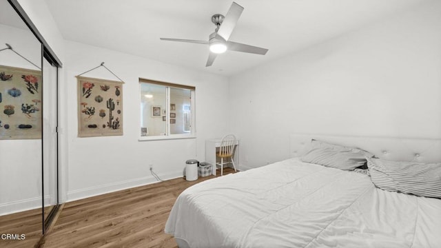 bedroom featuring a ceiling fan, baseboards, and wood finished floors